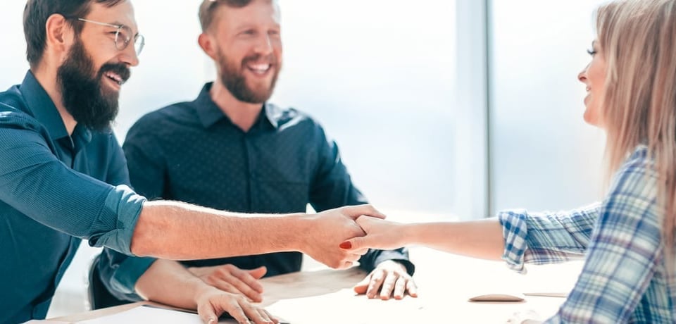 Personas estrechando manos en reunión de trabajo.